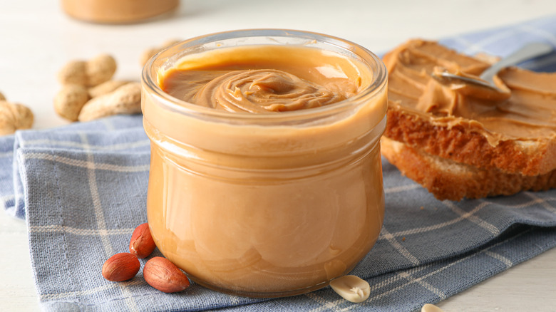 Peanut butter in jar next to toast