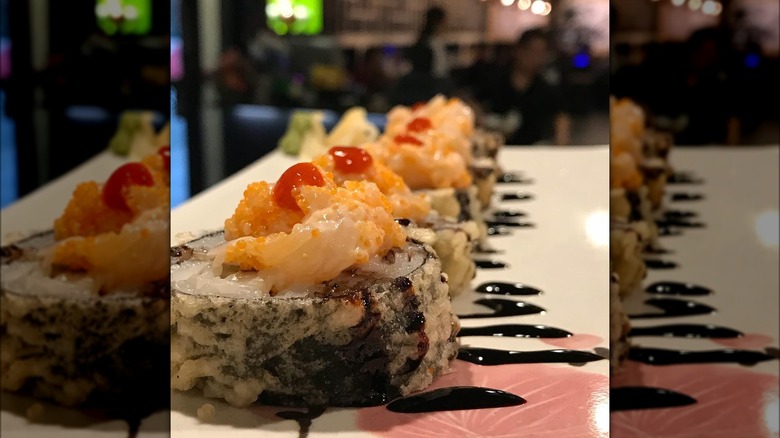 Salmon sushi roll with soy sauce on top in restaurant