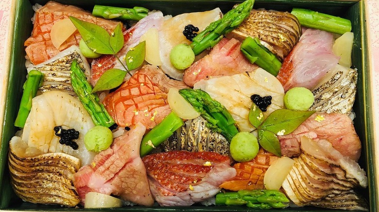 Box with different types of salmon and asparagus on top