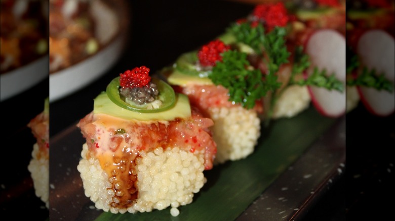 Sushi board with octopus nigiri, decorated with chives and avocado.