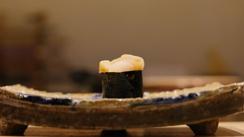 Uni, sea urchin roe bite covered in algae on a decorative plate.