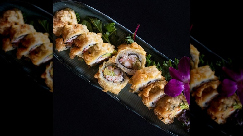 Deep-fried roll with shrimp on a decorative tray with a purple flower
