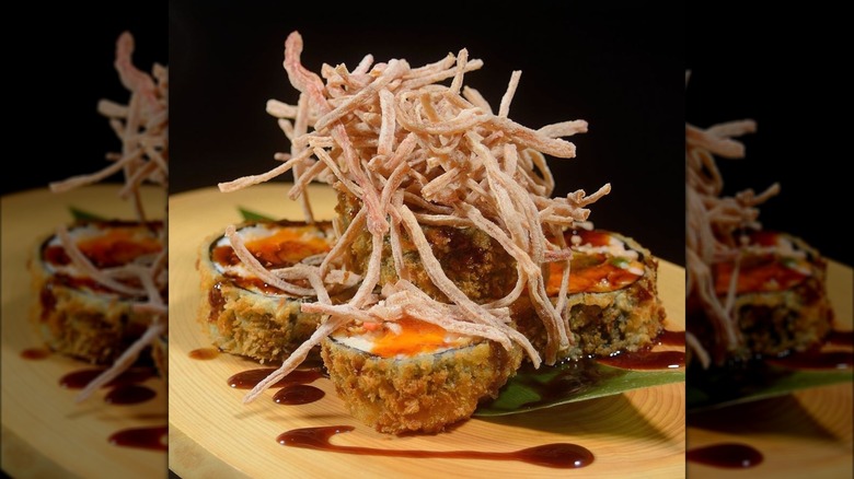 Deep-fried tempura rolls with a crispy shredded garnish on top of the rolls