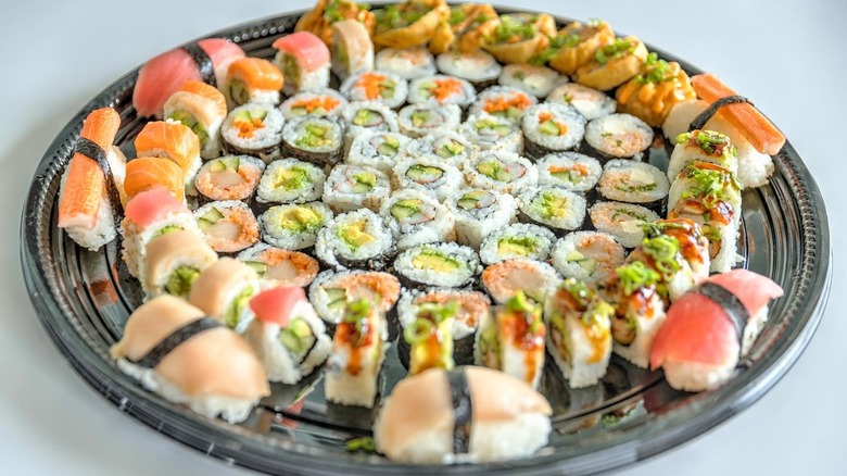 A tray of assorted sushi rolls in a circular shape, with several nigiris on the outside