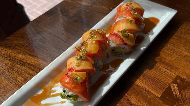 Momotaro roll made with avocado, cucumber, spicy mayo On top: New Zealand salmon, peach, eel sauce and Thai chilis.