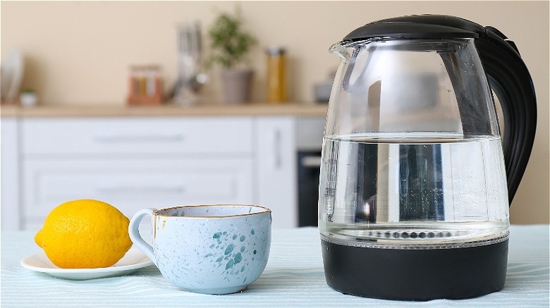 glass kettle with tea cup and lemon