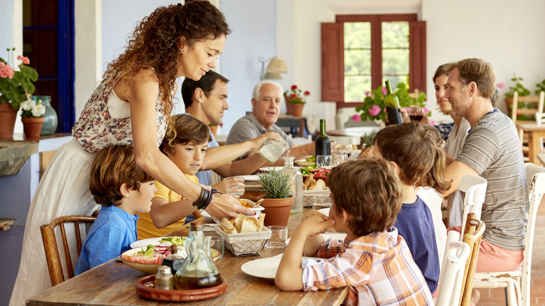 smiling mother serving food to large family