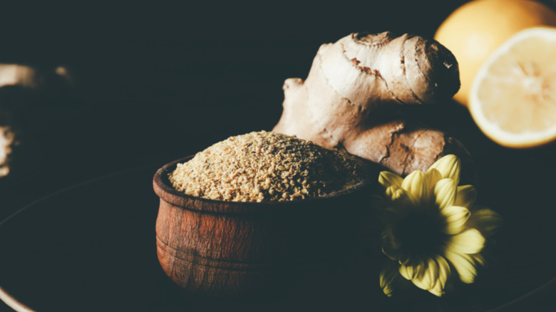 homemade seasoning in a bowl with a flower, ginger root and half lemon nearby
