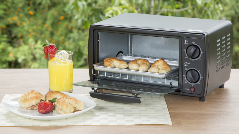open toaster oven with croissants on outdoor table