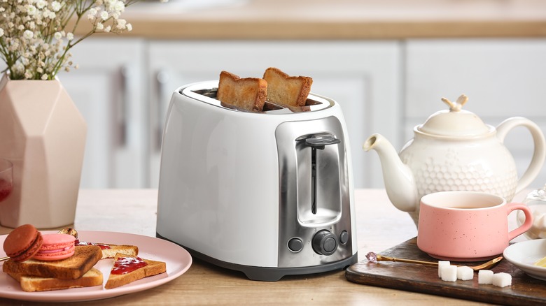 A white toaster in a kitchen surrounded by food