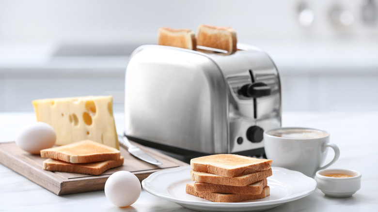 A toaster with toast inside surrounded by breakfast ingredients