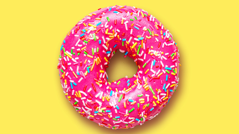 strawberry-iced donuts with sprinkles against yellow background