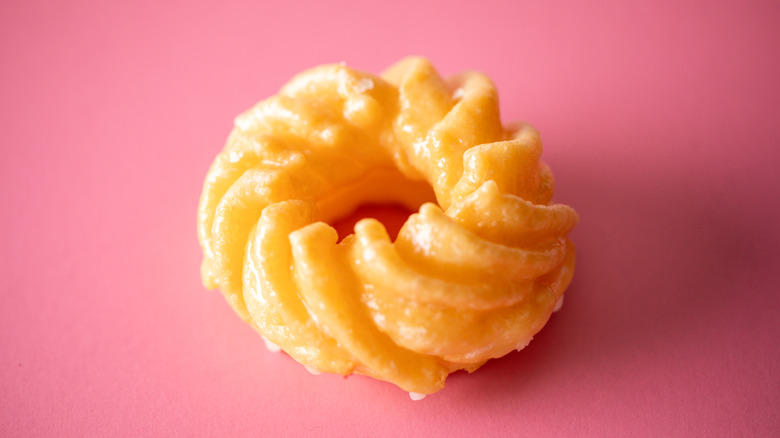glazed cruller on pink background