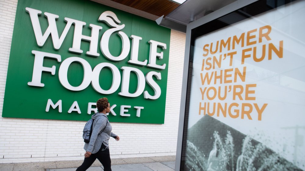 woman walking past a Whole Foods sign