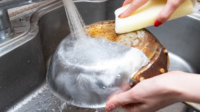Person cleaning pan with sponge 