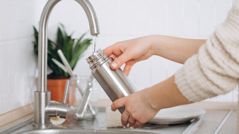 woman washes reusable water bottle 