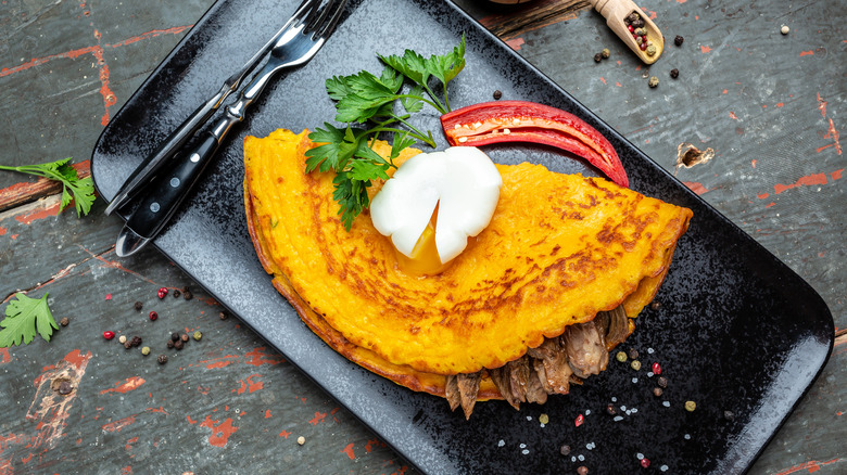 Folded over omelette on metal slab with fork
