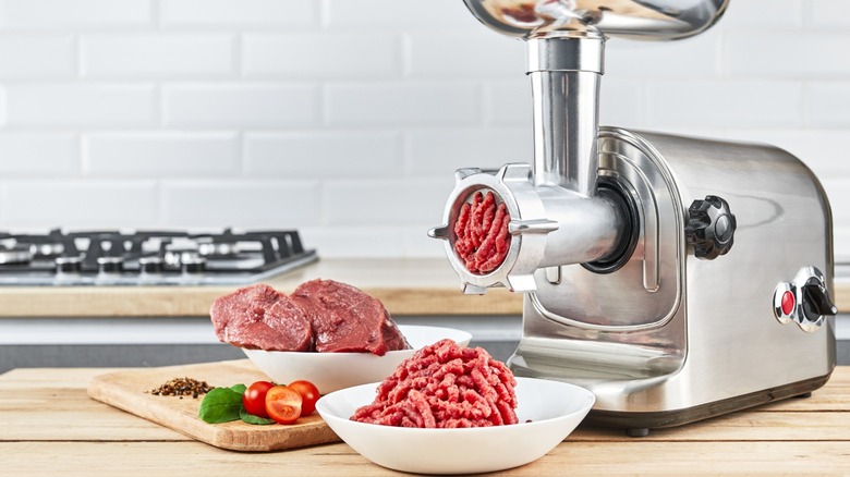 Cuts of meat with meat grinder and ground meat on a counter