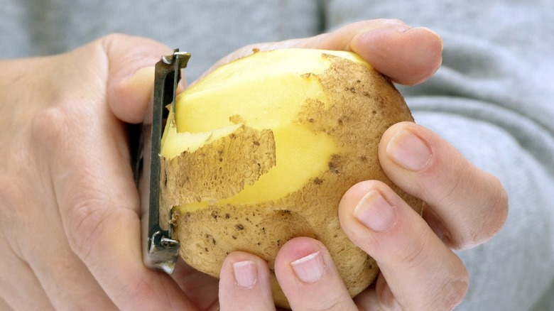 Person peeling potato with two hands