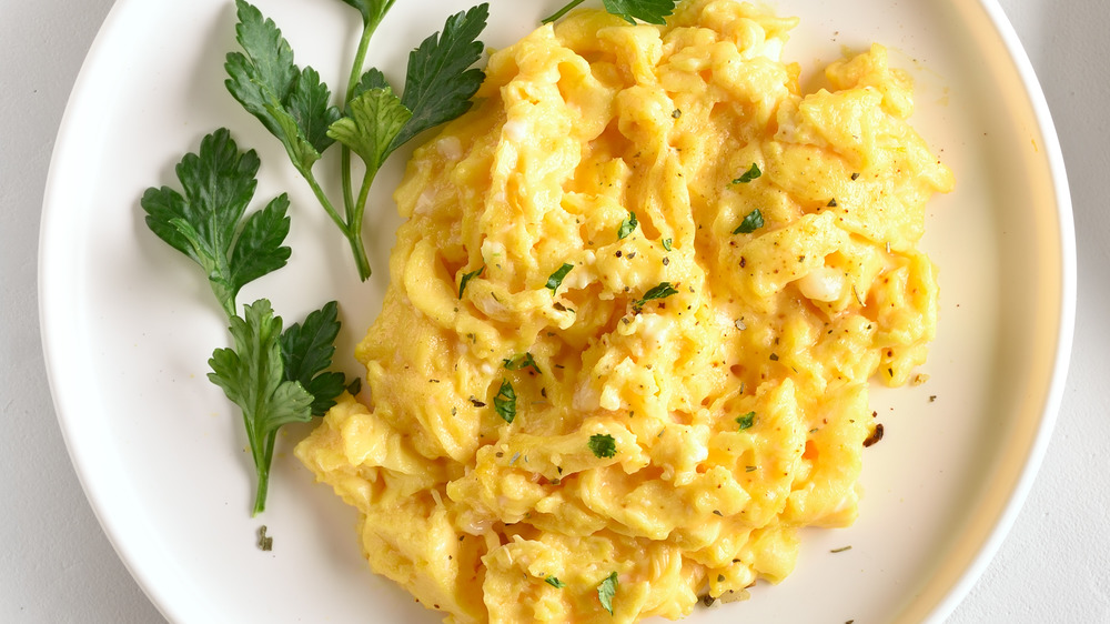 Two plates of scrambled eggs dressed with parsley