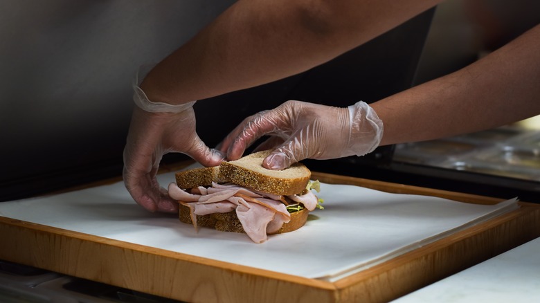 Deli worker wrapping sandwich