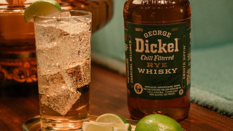 Bottle of George Dickel Rye Whiskey with cocktail and sliced limes