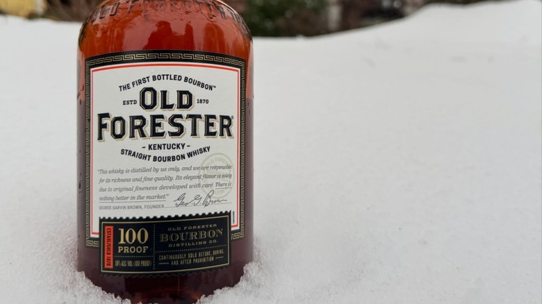 Bottle of Old Forester 100 Proof Kentucky Straight Bourbon Whiskey in the snow