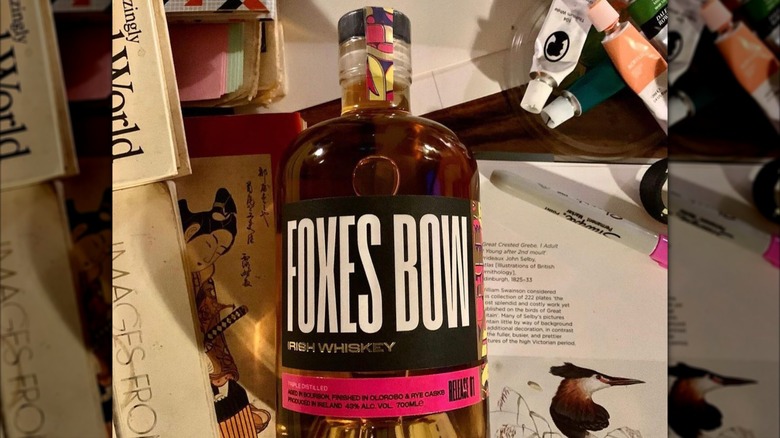 Foxes Bow bottle on table with books and cards
