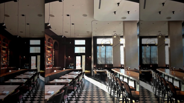 Cozy, elegant, and spacious interior at Lucian Books and Wine. Empty bartop and tables with built-in bookshelf in wall.