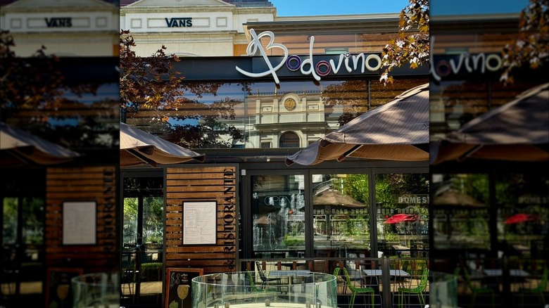 Bodovino outdoor seating area with tables, umbrellas, and firepit outside restaurant entrance