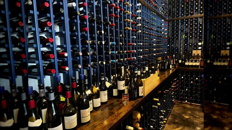 A wine cellar with assorted wines, and a counter with wine bottles on top.