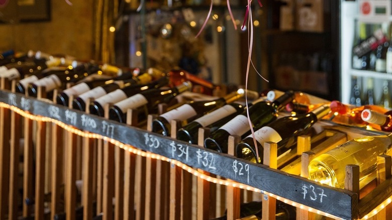 Wine bottles displayed on wine crate racks, with prices listed in chalk beneath display bottles