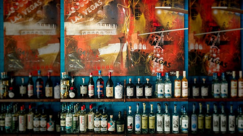 2 shelves with wines and spirits, and a painting in the background with the words "Las Vegas in it".