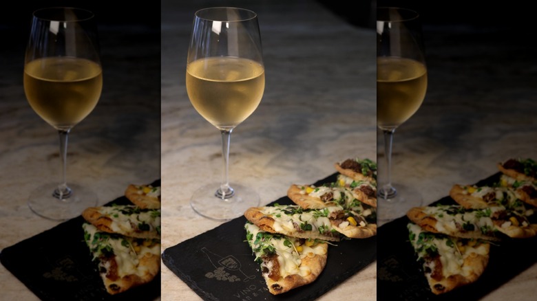 A glass of white wine and a small plate of appetizers.