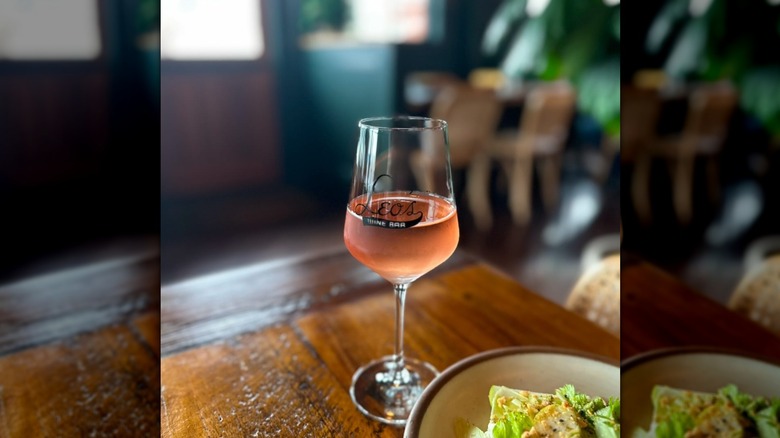 A glass of pink wine. The glass has a logo that reads Leo´s Wine Bar