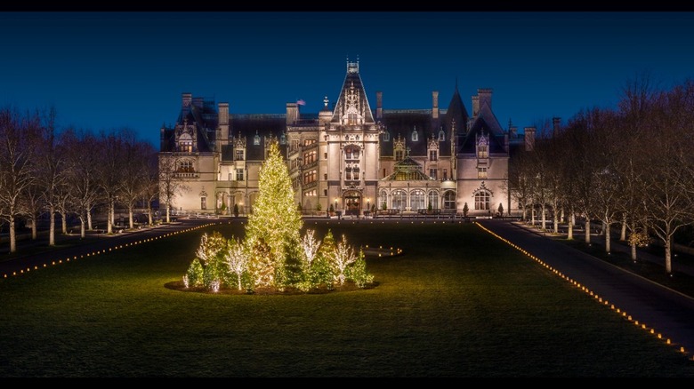 The Biltmore estate lit up at night with a large decorated Christmas tree in front of it
