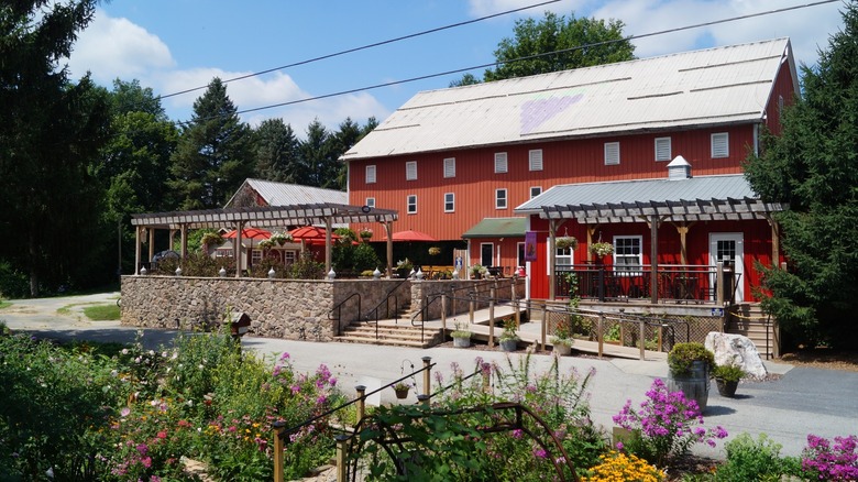 A red barn with a stone patio and colorful flowers