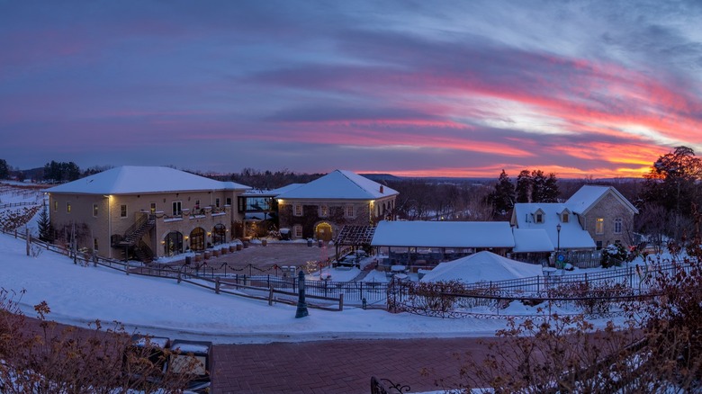 A snow-covered winery at sunset with pink and purple skies
