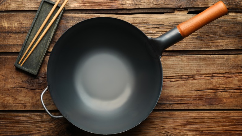 Wok on wooden table with chopsticks