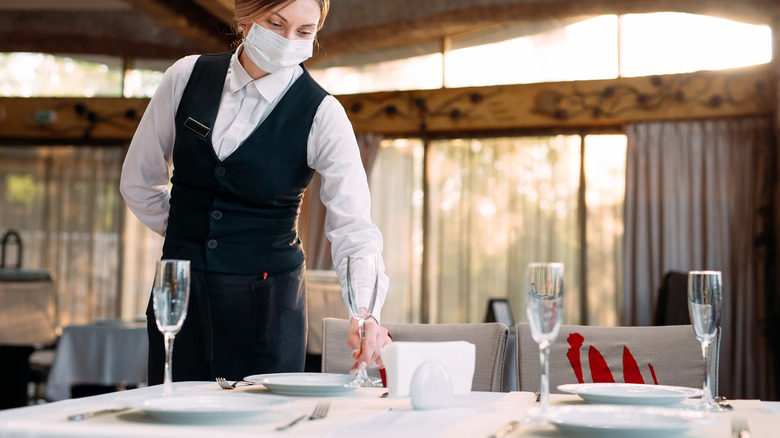 Person setting a table with glasses