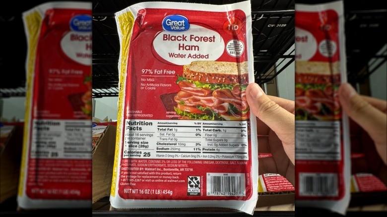 Hand holding red package of Great Value black forest ham