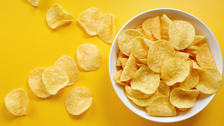 Potato chips in bowl on yellow background