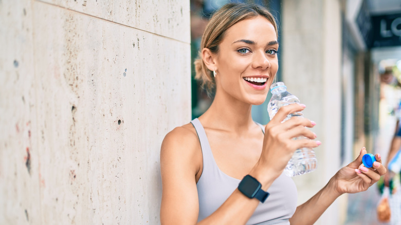 Woman drinking from plastic water bottle