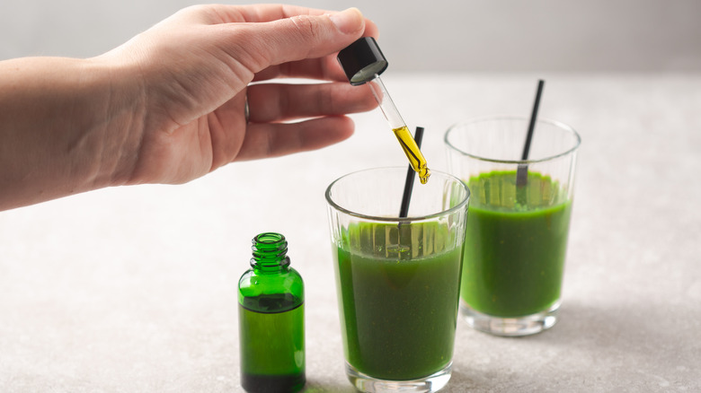 Person using eyedropper to add CBD to glass