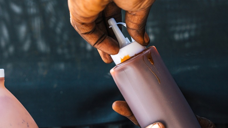 hands holding BBQ sauce bottle