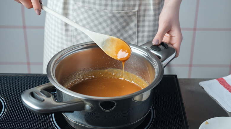 woman preparing candy in a pot and apron