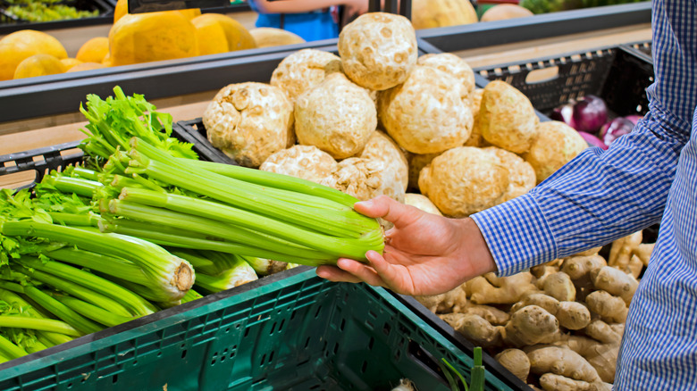 person picking up celery stalk in grocery store