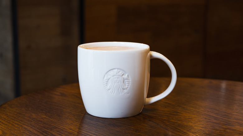Ceramic Starbucks mug sits on one of the chain's wooden tables.