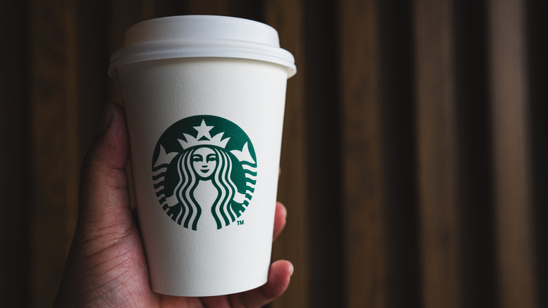 Hand holds a takeout cup of Starbucks coffee.