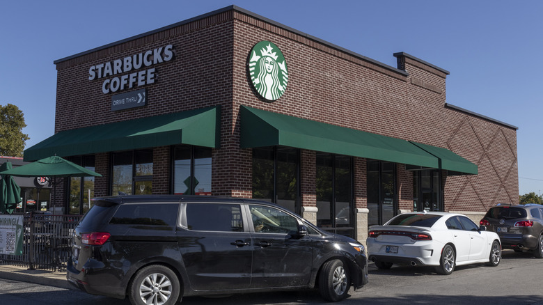 Cars line up outside a Starbucks drive-thru during the day.